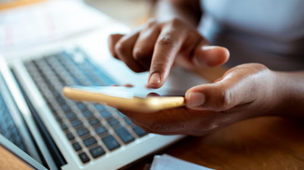 Hands browsing phone and laptop